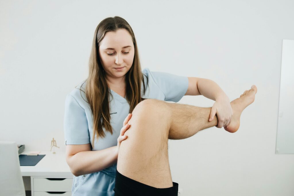 A physiotherapist assisting a patient's leg therapy session indoors, focusing on rehabilitation.